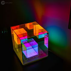 a multicolored cube shaped object sitting on top of a black table next to a lamp