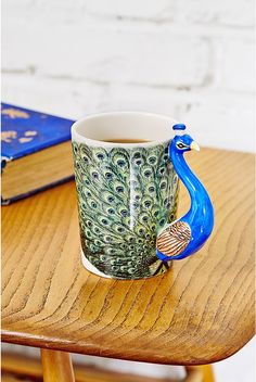 a peacock mug sitting on top of a wooden table