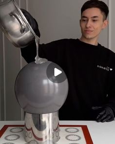 a man pours liquid into an apple shaped object on top of a white table