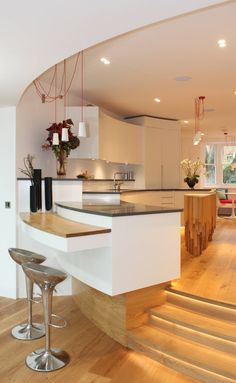 an open kitchen and living room with stairs leading up to the dining room, which also has wood flooring