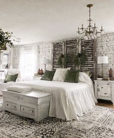 a bedroom with white brick walls and green pillows on the bed, along with an antique trunk coffee table