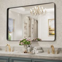 a bathroom vanity with a large mirror above it and flowers in the vase on the sink