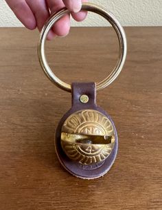 a hand holding a metal keychain on top of a wooden table