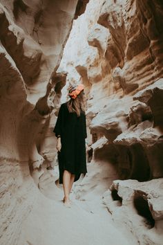 a woman walking through a narrow slot in the desert