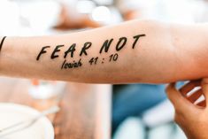 a person with a tattoo on their arm that says fear not