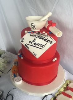 there is a red cake with white decorations on the top that says congratulations laurel and it's made out of fondant