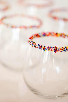 several wine glasses filled with colorful beads and confetti on the rims are lined up