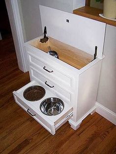 an oven built into the side of a wall next to a dog bowl and dishwasher