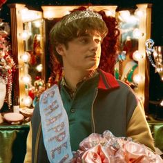 a young man wearing a tiara and holding a bouquet