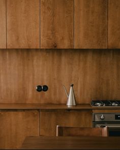 a kitchen with wooden cabinets and a stove top oven next to a tea kettle on a counter