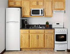 a white refrigerator freezer sitting next to a stove top oven in a kitchen with wooden cabinets