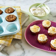 cupcakes with white frosting in muffin tins on a pink plate