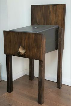 a small wooden table with an open drawer on the bottom and one leg in front of it