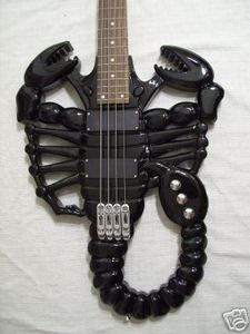 an electric guitar shaped like a scorpion on a white sheet with black beads around it