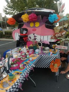 a table that has some decorations on it and people around it with plates and cups