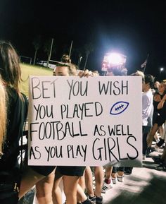 a group of people standing around each other holding up a sign that says bet you wish you played football as well as you play girls