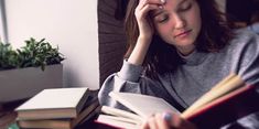 a woman sitting at a table with an open book in front of her and reading