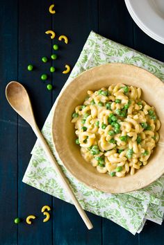 a bowl filled with macaroni and peas on top of a napkin next to a spoon