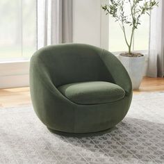 a green chair sitting on top of a rug in front of a potted plant