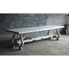 a white table sitting on top of a cement floor next to a wooden chair and wall