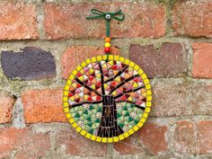 a colorful stained glass tree ornament hanging on a brick wall