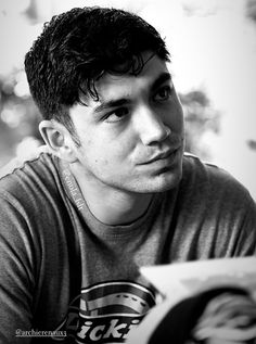 black and white photograph of a young man reading a book while looking at the camera