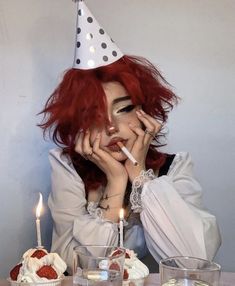 a woman with red hair wearing a party hat and holding her hand to her face