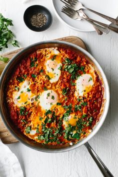 an egg dish is shown in a skillet on a cutting board next to other ingredients