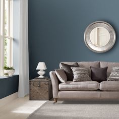 a living room filled with furniture and a round mirror on the wall above it's headboard