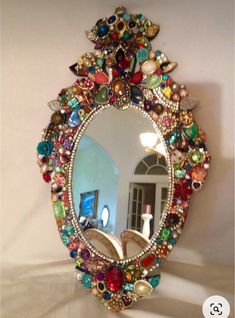 a mirror that has been decorated with many different colored beads and jewels on the frame