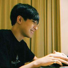 a young man sitting in front of a laptop computer with his hand on the keyboard