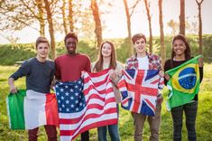 a group of people holding american and brazilian flags in the grass with trees in the background