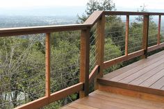 a wooden deck with metal railing overlooking trees