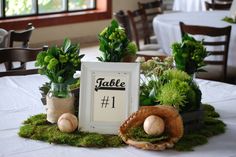 a table topped with plants and baseballs on top of a white table cloth covered table