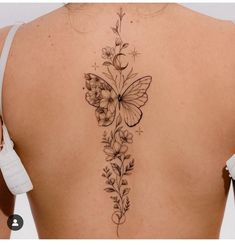 a woman's back with a butterfly and flowers tattoo on her left side ribcage