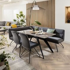 a living room filled with lots of furniture and plants on top of wooden flooring