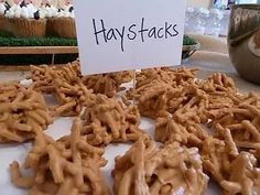 a table topped with lots of pretzels covered in frosting next to a sign that says haystacks