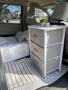 a bed and drawers in the back of a car