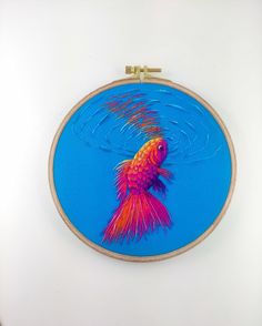 a colorful fish is in the middle of a blue hoop hanging on a white wall