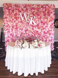 a table with flowers on it in front of a wall that says w & k