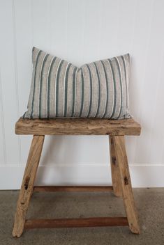 a wooden bench with a striped pillow on it