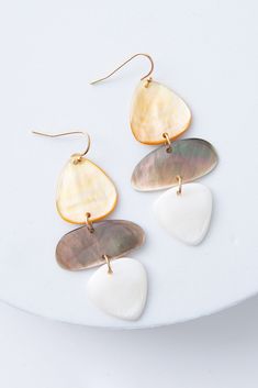 The Shell Stack Earrings are dangly earrings with brass ear hooks. Three flat pieces of shell are stacked on top of each other for a sculptural look. The top piece has caramel hues, the middle has grey hues, and the bottom has white hues. Each piece is connected by a brass ring. Luxury Silver Shell Jewelry, Sea Shells Earrings, Modern White Mother Of Pearl Earrings, Elegant White Shell Earrings, Chic Beige Dangle Jewelry, Stack Earrings, Coffee Gifts Card, Neutral Color Palette, Stacked Earrings