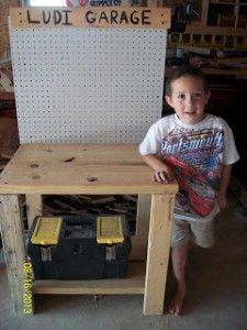 a young boy standing in front of a wooden workbench with the words diy garage workspace on it