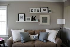 a living room filled with furniture and framed pictures on the wall above it's windows