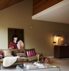 a living room filled with furniture and a painting on the wall above it's coffee table