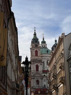 a city street with tall buildings and a clock tower in the background