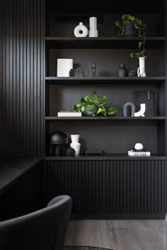 a black shelf with plants and vases on it