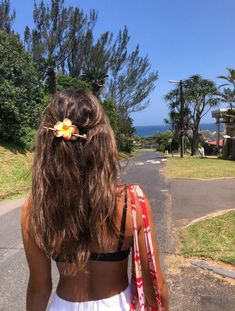 a woman walking down the street with her hair in a flower pinned to her back