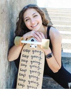 a woman sitting on the steps holding a skateboard that says keep going, keep going and keep going