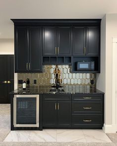 a kitchen with black cabinets and marble counter tops